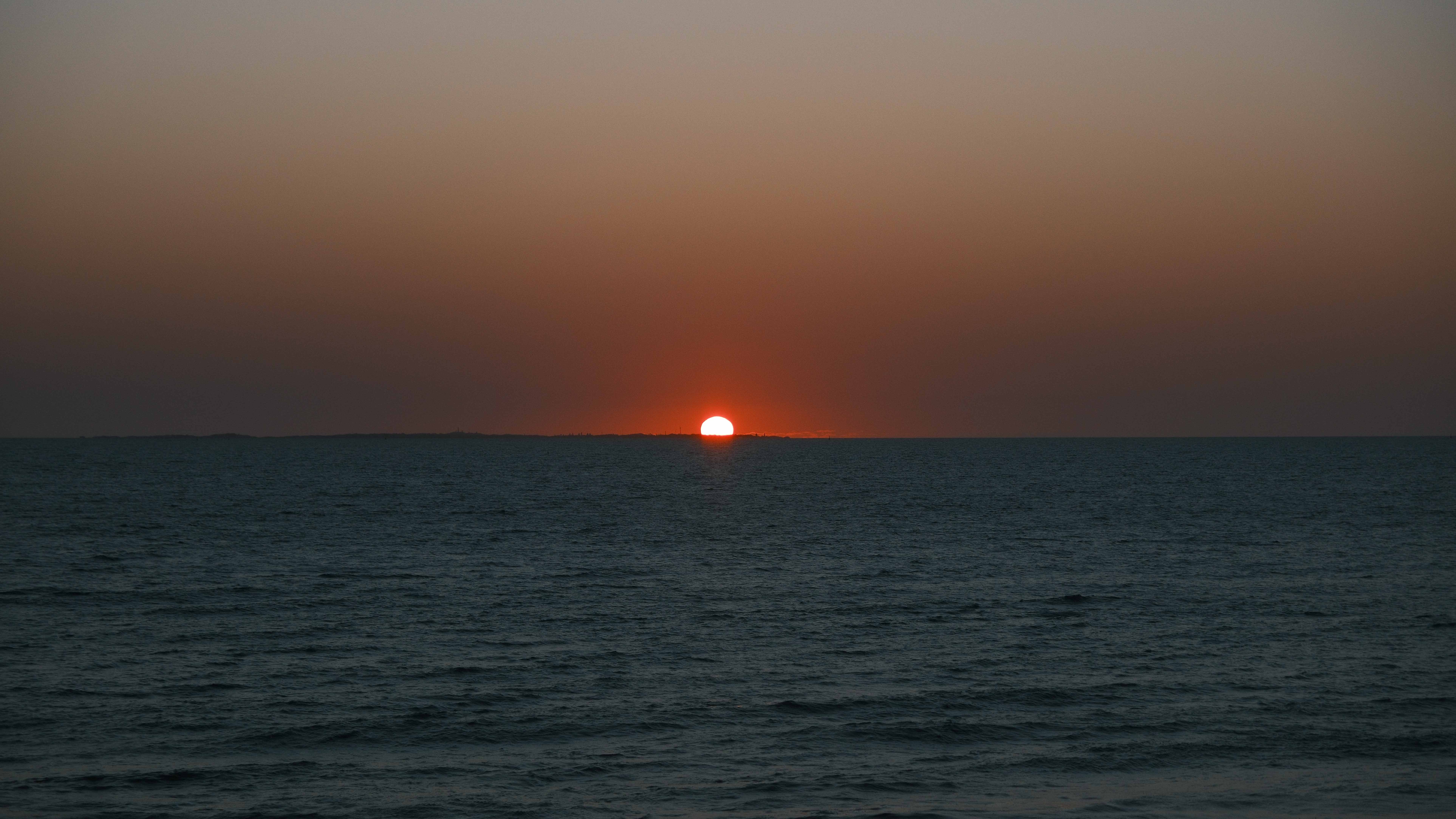 The sun disappearing below the horizon