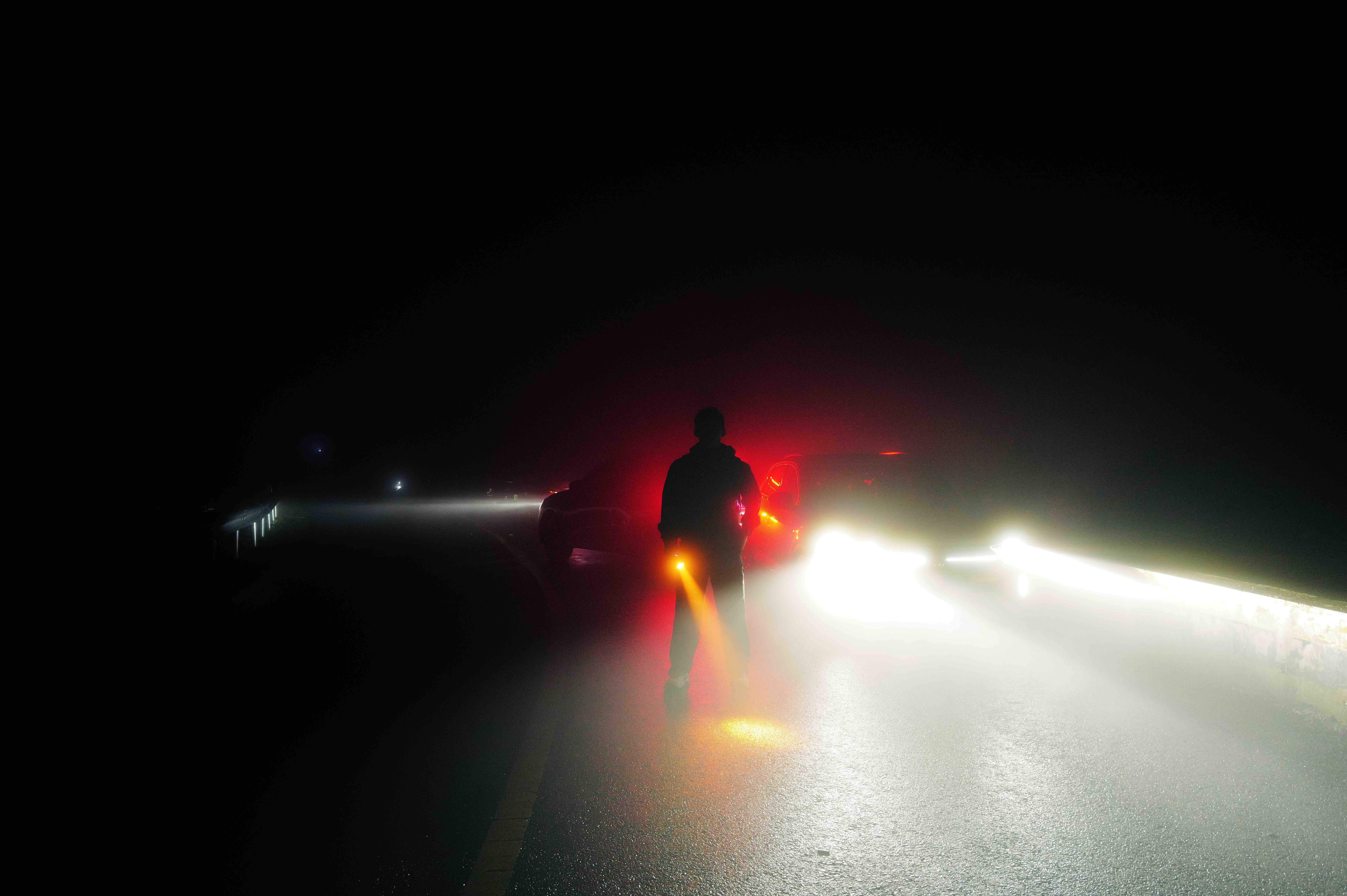 A figure silhouetted against headlights