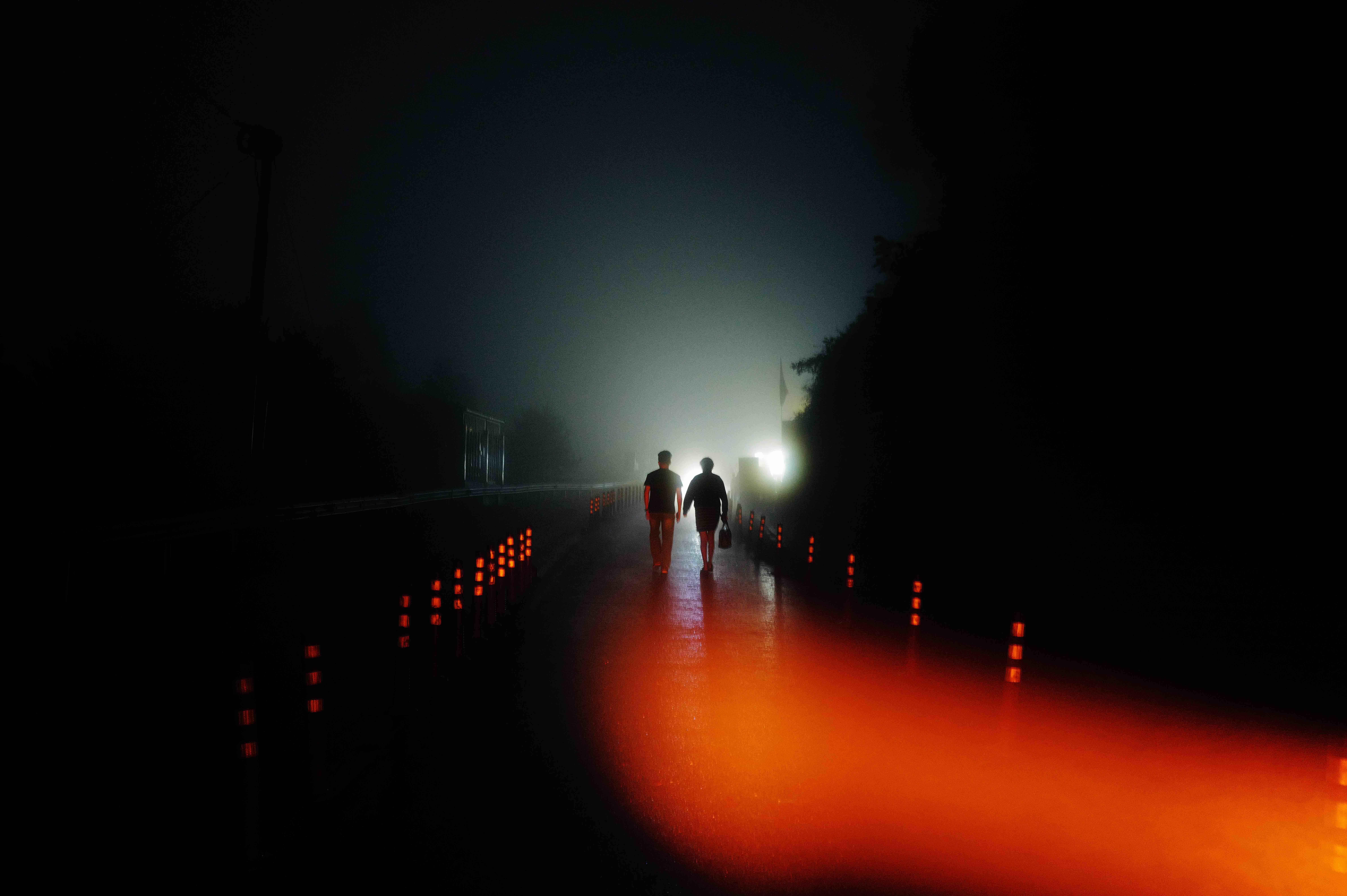 Two people walking along a road illuminated in red